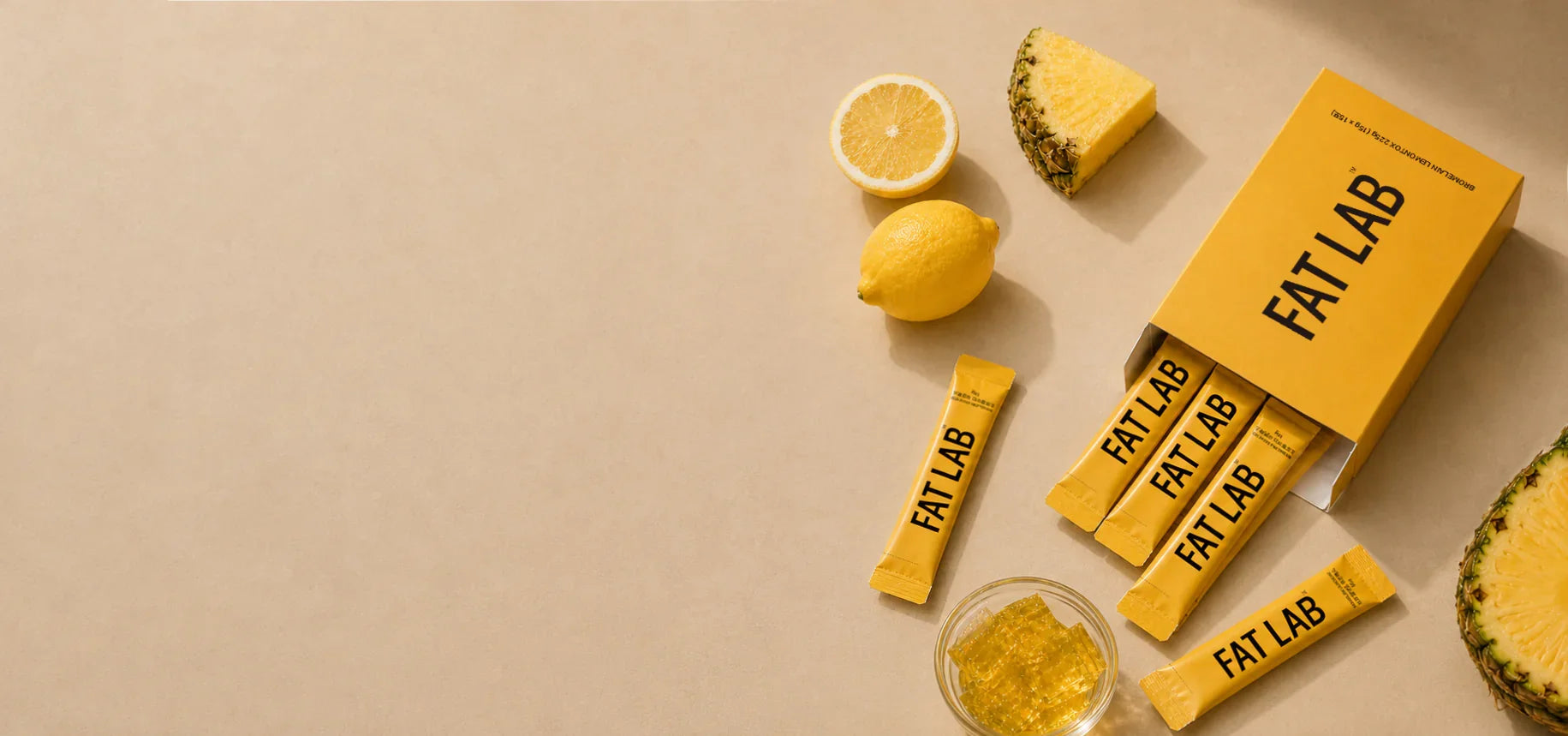 FATLAB Bromeliad Lemontox probiotic jelly with lemon, pineapple, and yellow product packaging on a beige studio background